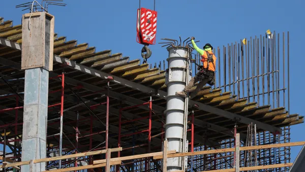 A construction worker climbing a support structure for a building.