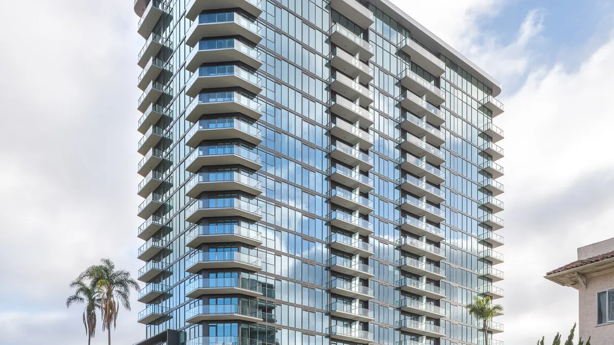 A modern, high-rise apartment building with balconies and glass walls.