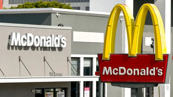 An image of a McDonald's with a sign in the forefront and a gray building in the background.