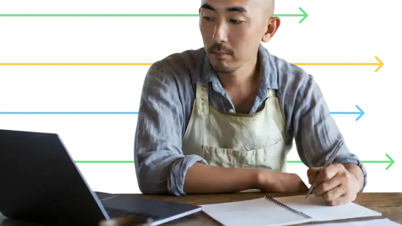 Person wearing an apron using notebook and laptop