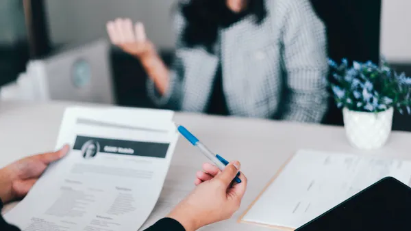 A person sits in a job interview, with their resume visible