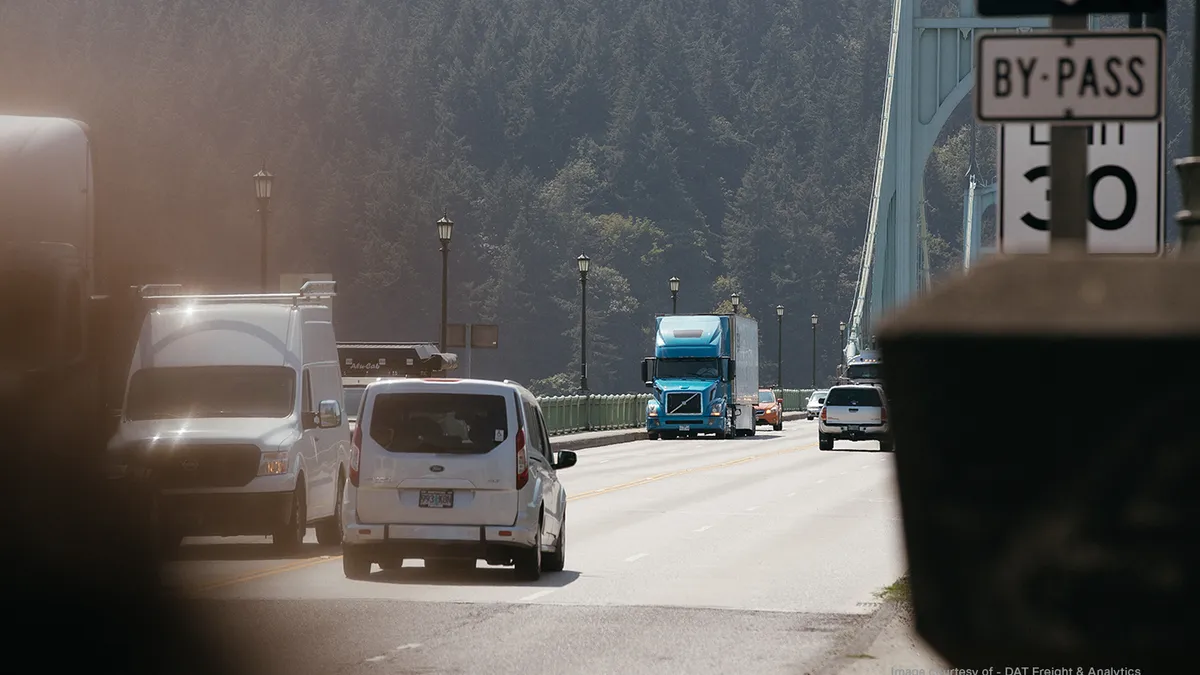 A truck crosses a bridge with passenger vehicle traffic nearby.