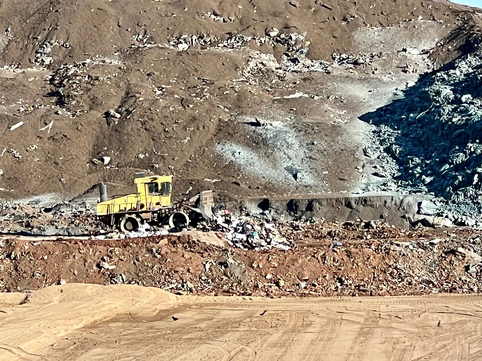 Heavy equipment pushes waste into a landfill cell that has a geothermal liner