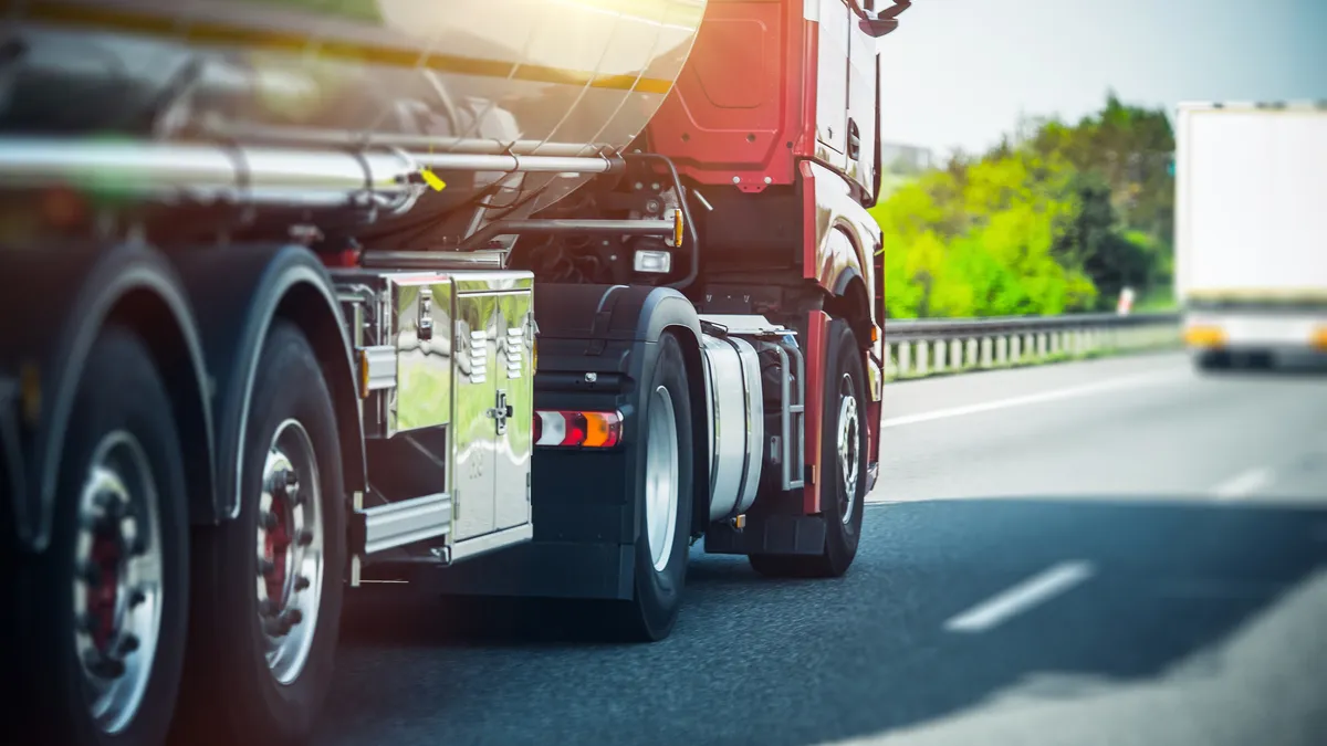 An large semi-truck with a red cab on the highway in the sun.