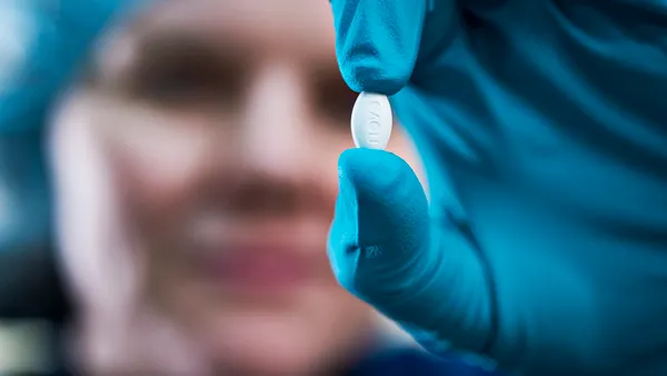 A pill of Rybelsus, a Novo Nordisk medicine containing semaglutide, is held by a gloved hand.