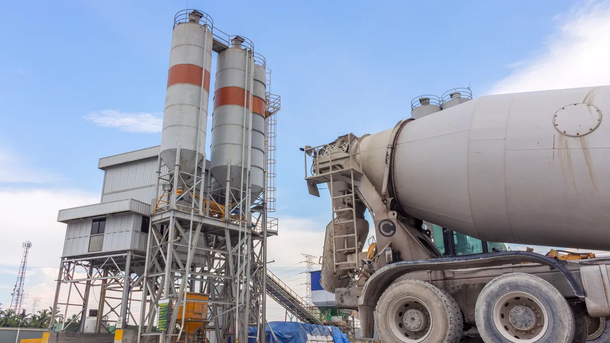 A cement mixer in front of an industrial plant.