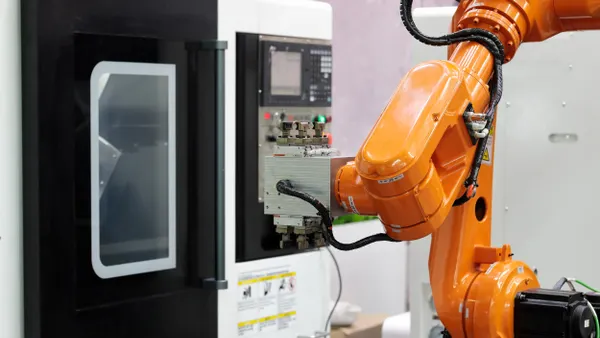 An orange robotic arm at a manufacturing facility