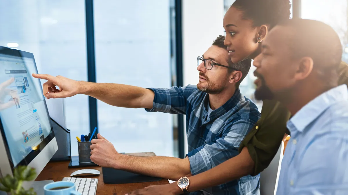 Cropped shot of three businesspeople working around a computer in the office