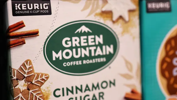 Boxes of Green Mountain Keurig coffee K-Cup pods displayed on a store shelf. The box lable reads "Keurig Genuine K-Cup Pods Green Mountain Coffee Roasters Cinnamon Sugar Cookie"