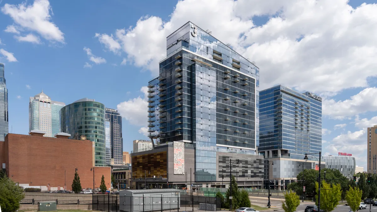 A tall glass-and-steel apartment building next to two othrers.