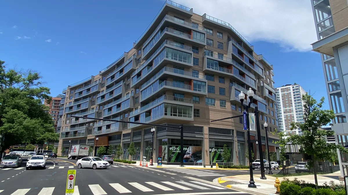 An apartment building with glass balconies on a street corner.