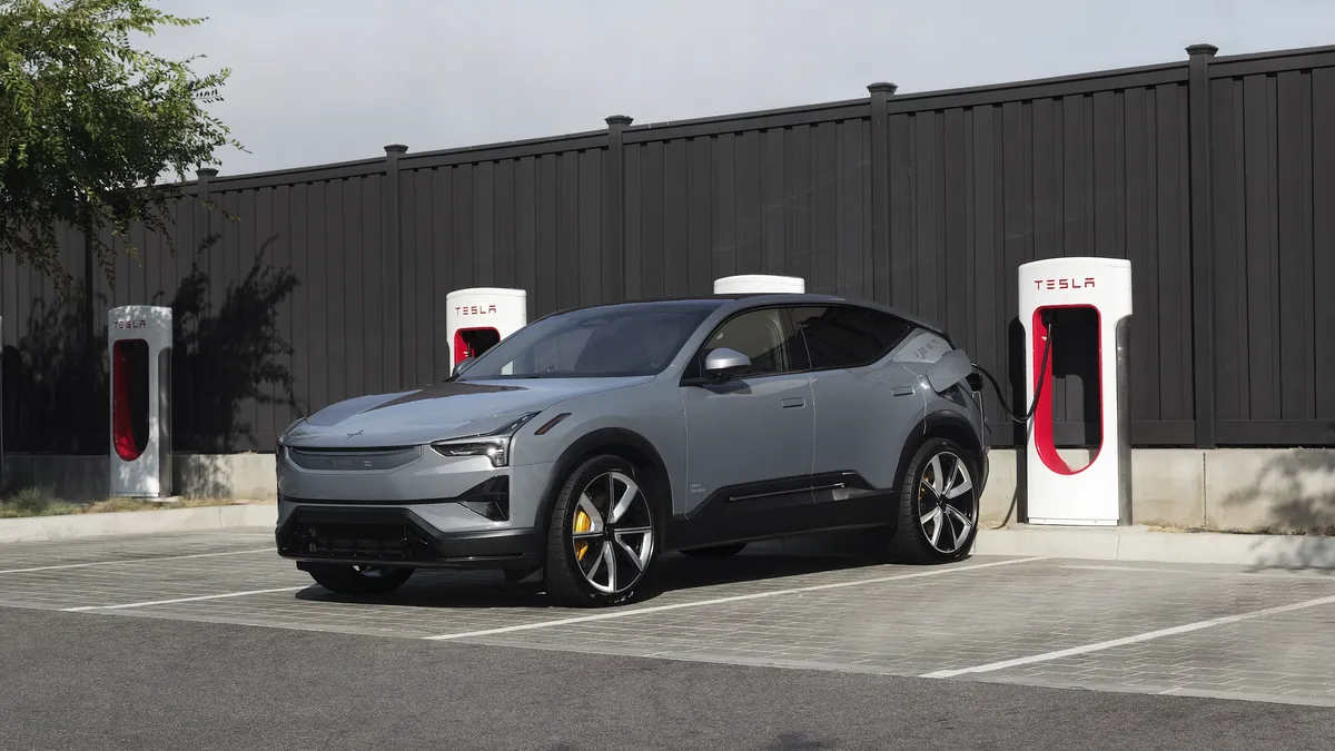 A Polestar 3 electric SUV plugged in for charging at a Tesla Supercharger location.