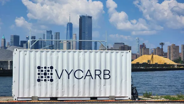 An image of a shipping container with Vycarb on the side and the New York City skyline in the background