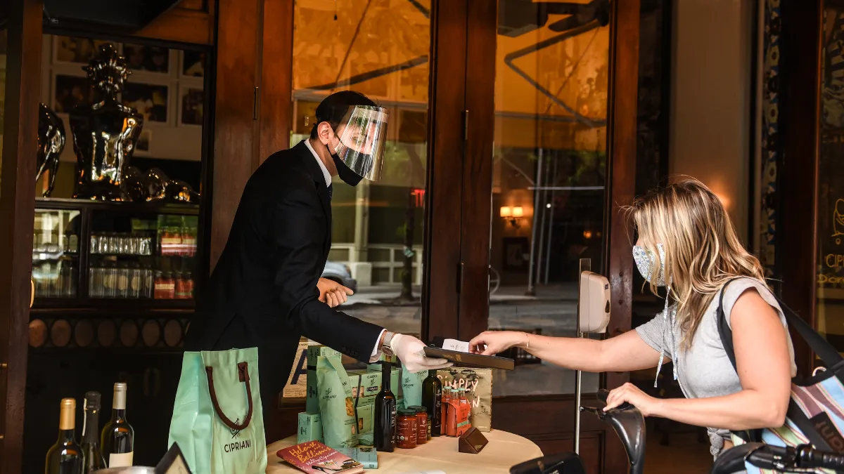 Person handing payment to waiter in outside restaurant setting.