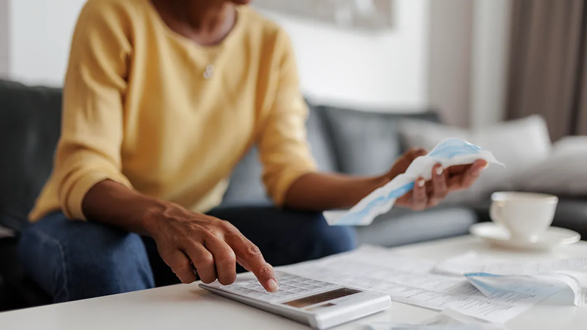 Person sitting on couch using a calculator and looking at receipts.