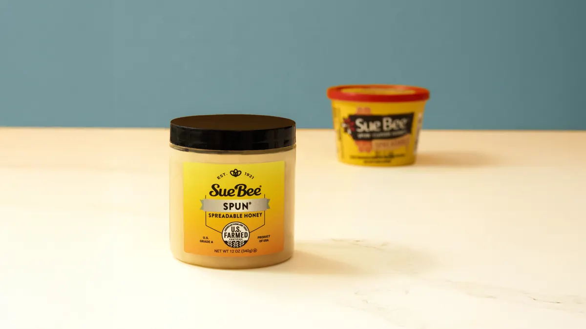 Two different containers of Sue Bee spun honey made of different plastics and featuring different looks.