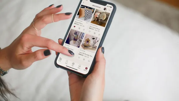 Person holding a mobile phone with the Poshmark website pulled up.