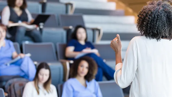 A college professor lectures to a room full of students.