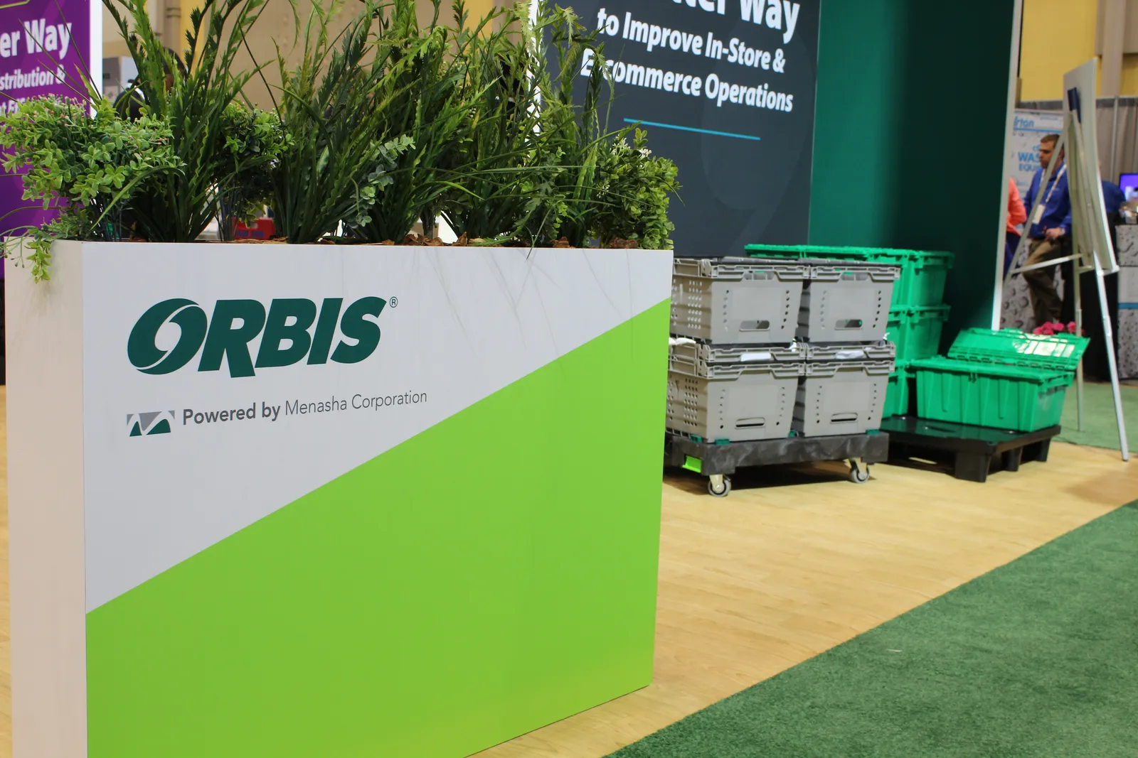 A stack of reusable transport totes at a convention display with branding for Orbis.