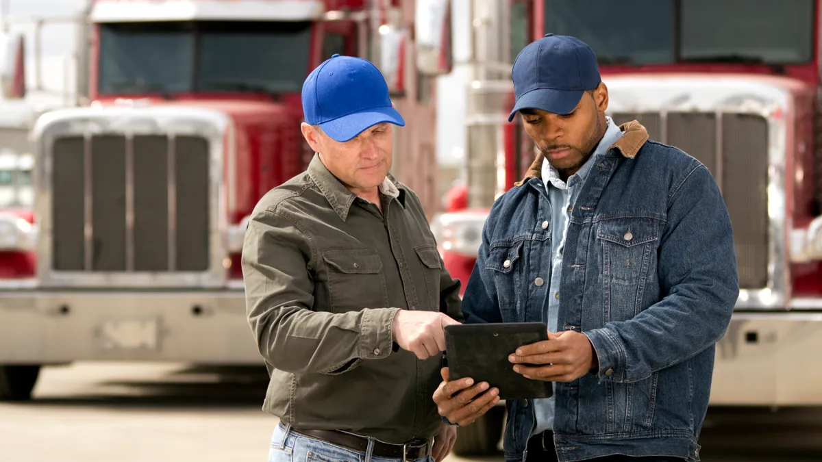 Two truck drivers having a meeting using a tablet computer.