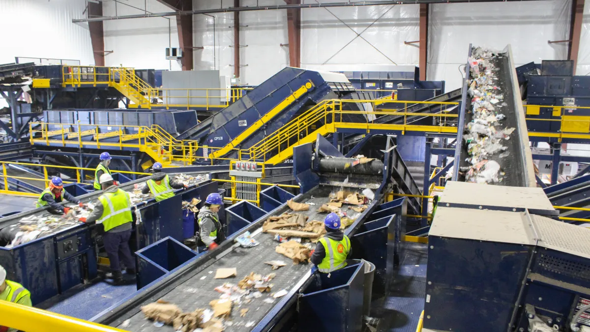 Workers standing next to conveyor belts sorting recyclables at LRS's new Chicago facility.