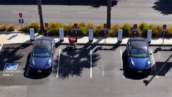 Electric vehicles sit parked at a Tesla charging station