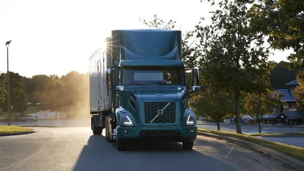 A Volvo VNR Electric truck at the American Trucking Associations' Management Conference & Exhibition with sunlight along the trailer.