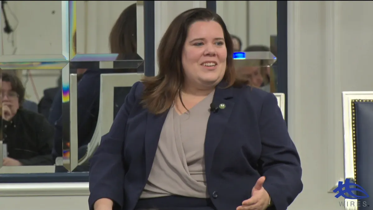 A woman speaks from a chair.