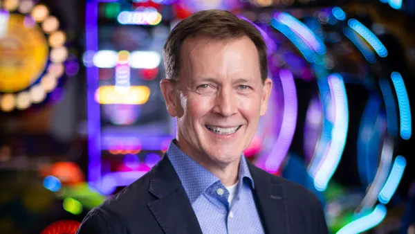 An image of a person in a suit standing in front of blurred arcade games.