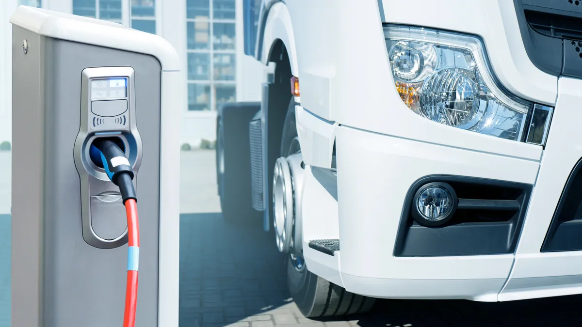 An electric truck charges at a charging station.