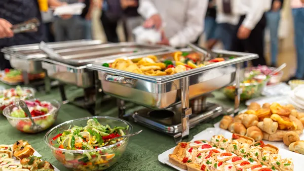 A stock image of catered food in chafing dishes.