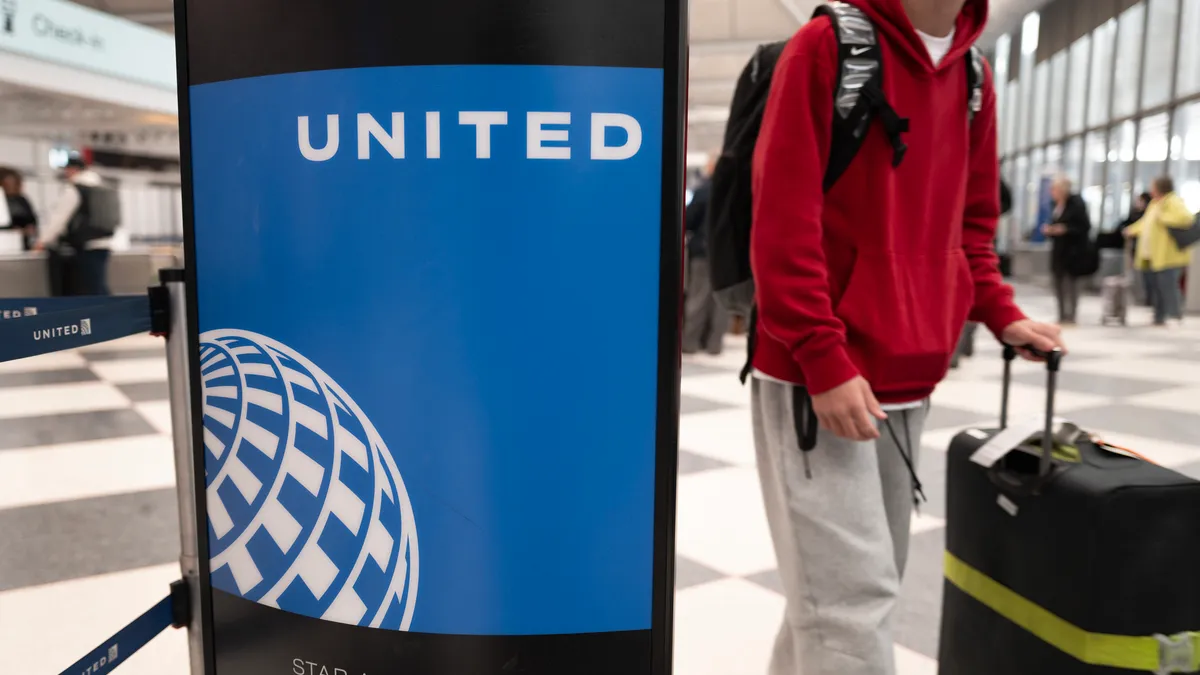 A passenger walks by a United Airline's sign in Chicago's O'Hare International Airport with luggage.