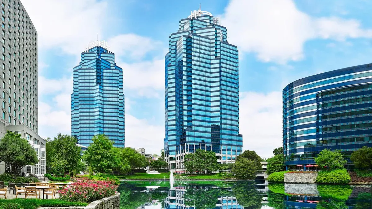 A pond reflects the image of the exterior of a hotel.