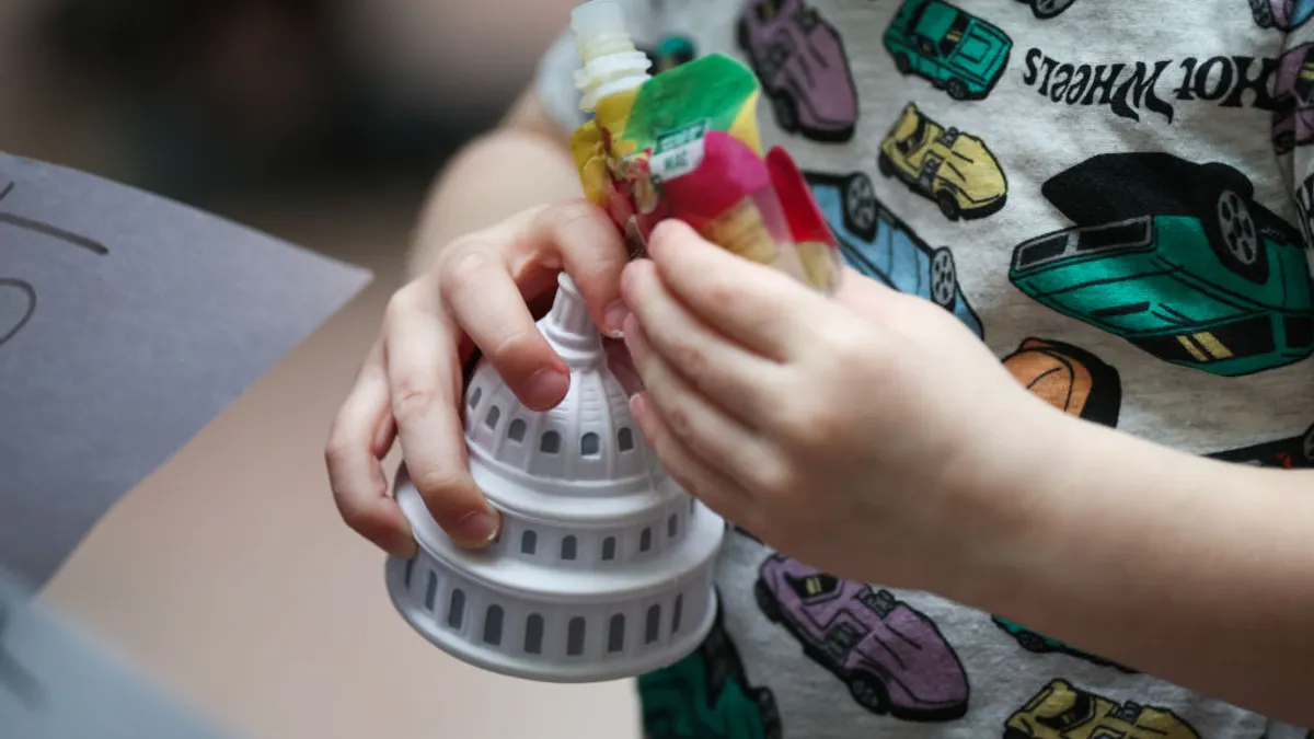 A close-up of a child holding a foam replica of the U.S. Capitol