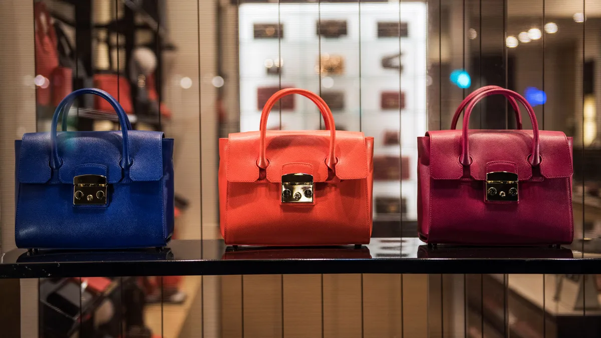 Three luxury handbags sit on a shelf.