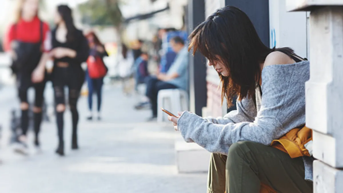 A woman uses her phone on the sidewalk.