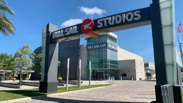Sign on arch reading "Full Sail Studios" with Full Sail University's logo featuring an airplane sillouette in orange circle.