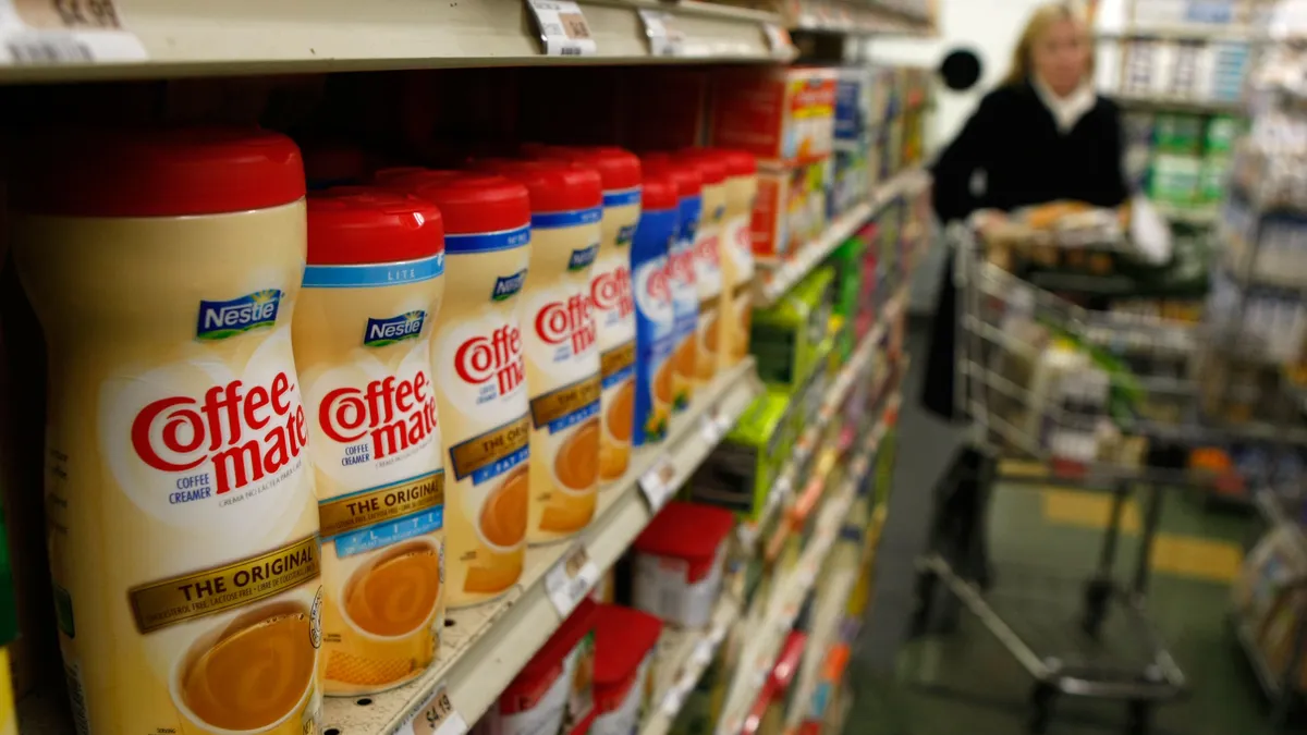 Containers of Nestle Coffee Mate coffee creamer are displayed on a shelf.