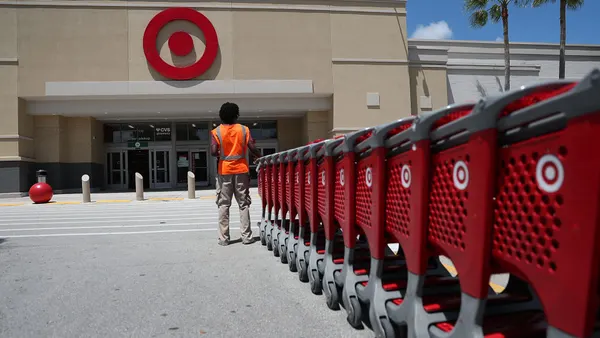 A Target store employee collects shopping carts in a parking lot.