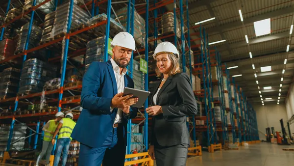 A businessman and a businesswoman discussing work in the warehouse using a digital tablet
