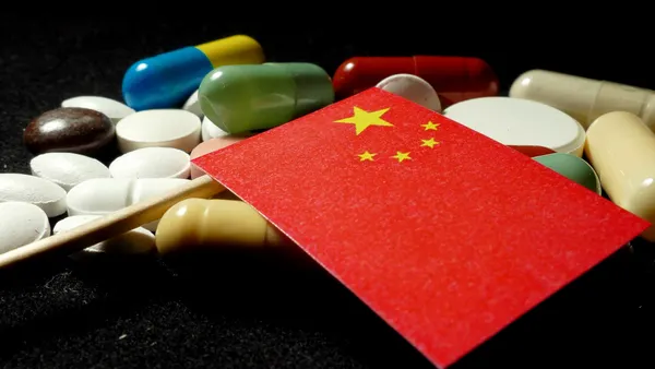 Chinese flag with lot of medical pills isolated on black background