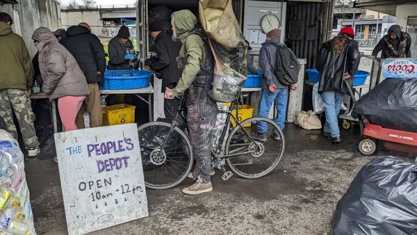 People drop off containers at an outdoor redemption center