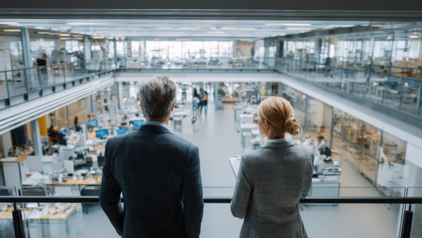 Two professionals overlooking a large modern workplace.