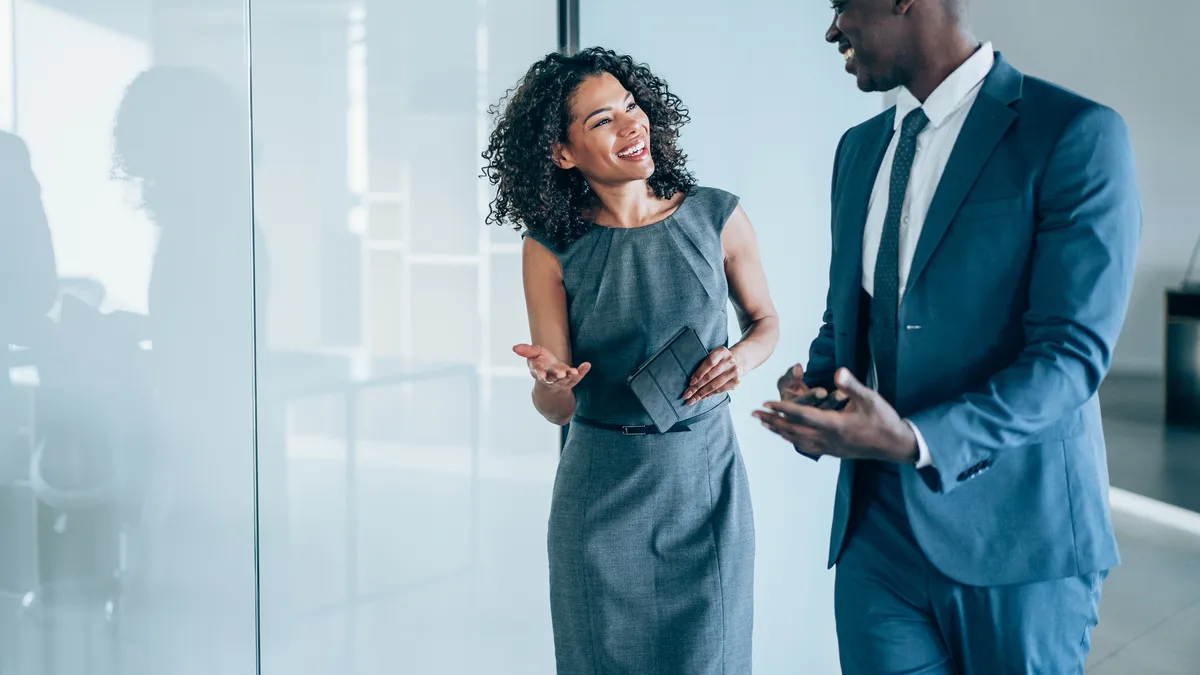 A general counsel and CEO talk while walking through a business office