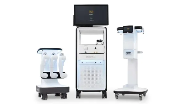 Three carts on wheels stand side by side, with one featuring robotic arms and another showing a screen and a controller.