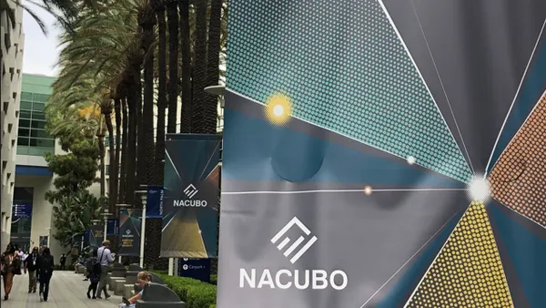 A sign for NACUBO conference amid palms, with conference-goers in the background.