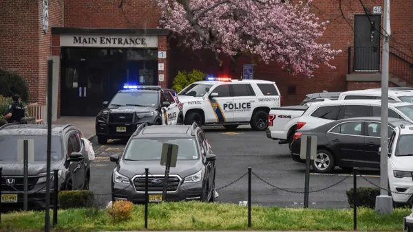 Police cars are parked near the main entrance of a school.