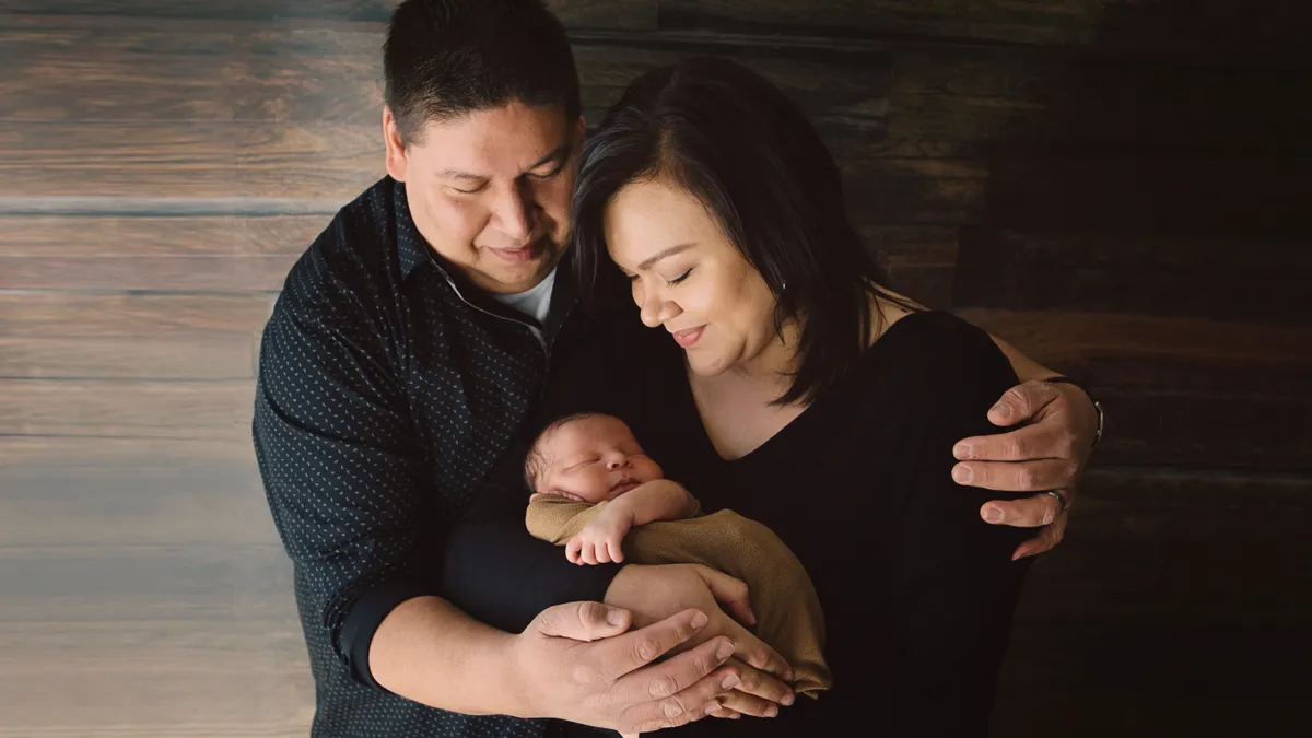 A Native American mother and father hold their newborn son