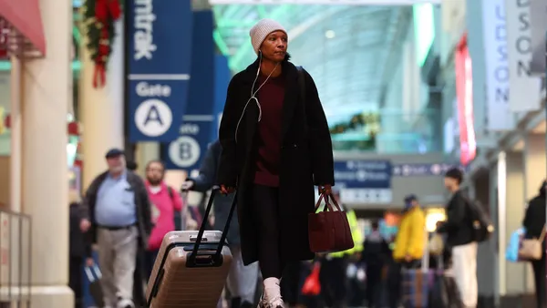 A person in a black coat pulls a suitcase.