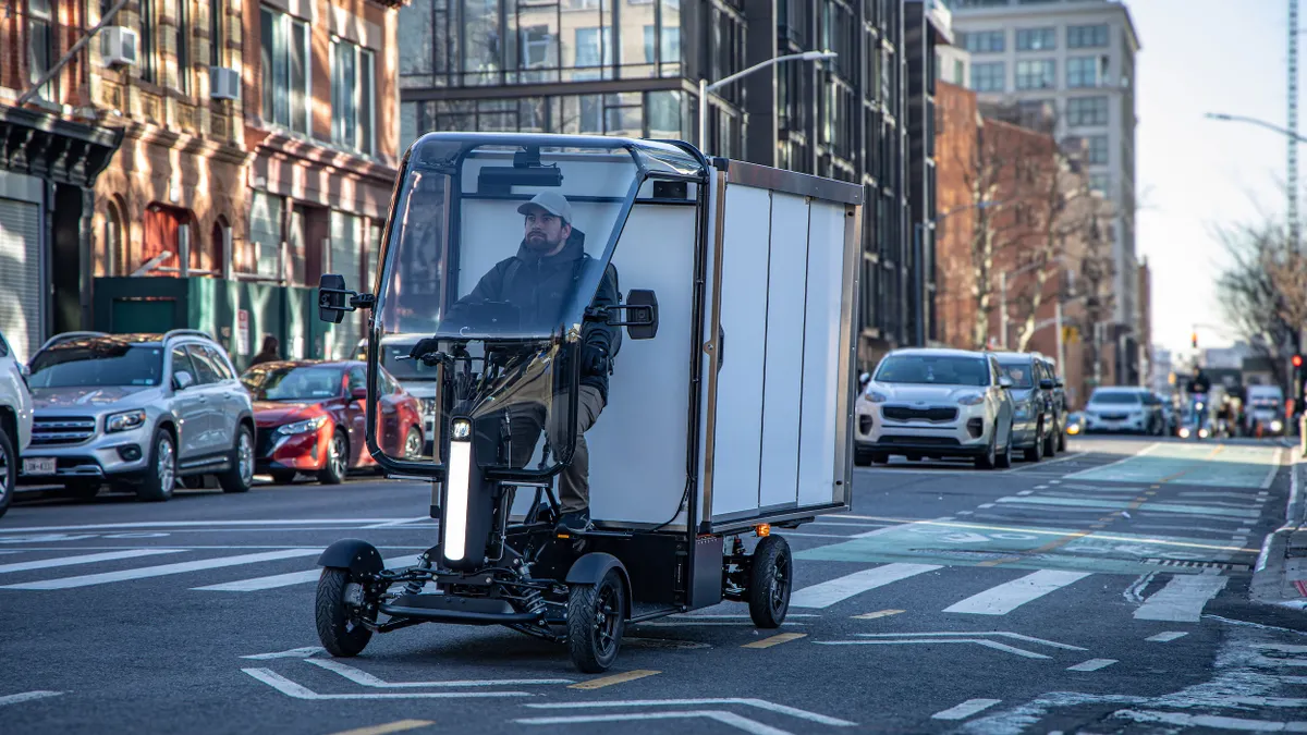 Man seated in a four-wheel cargo van in the bike lane of a New York City street.